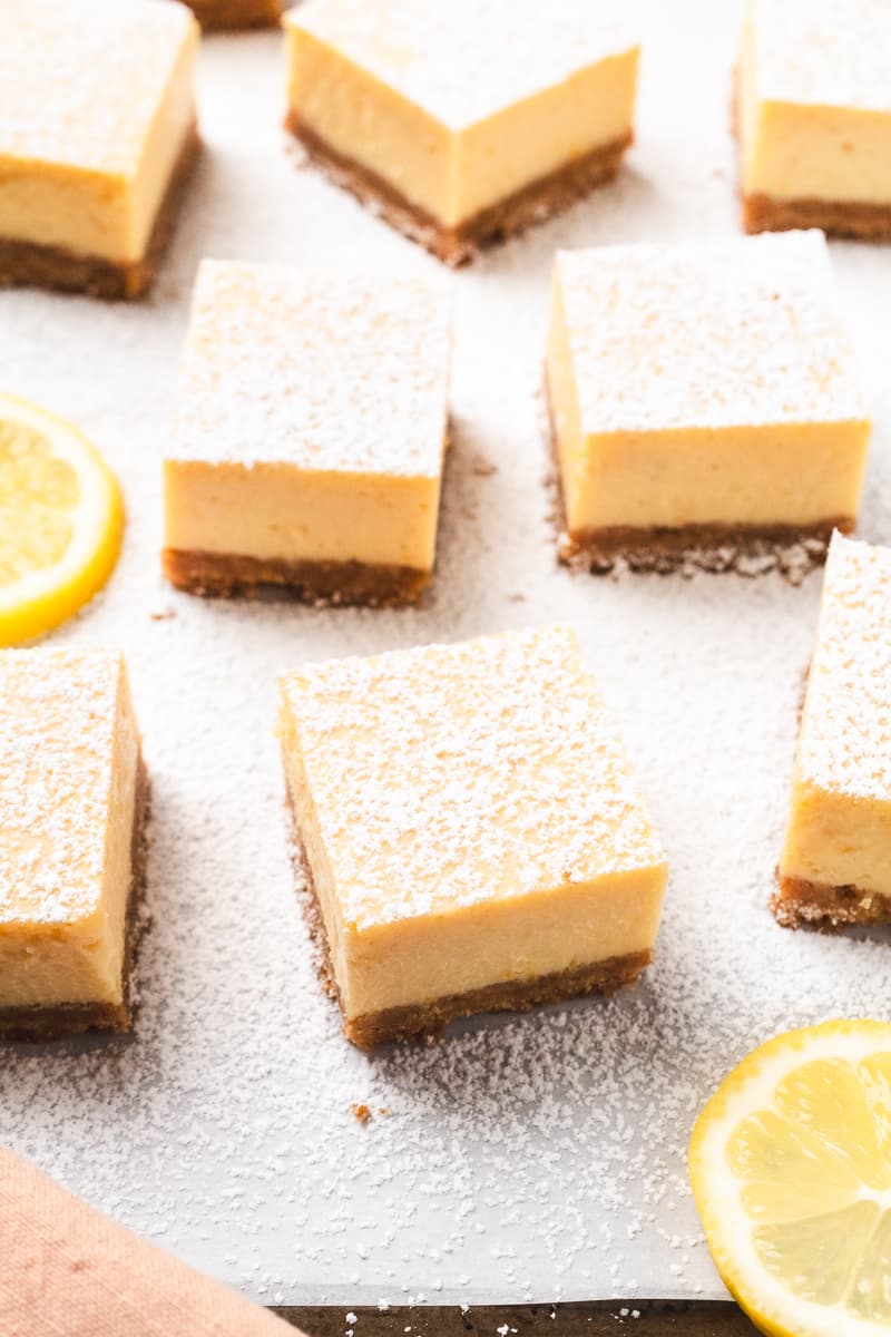 Neatly cut lemon bars topped with powdered sugar, arranged on parchment paper.