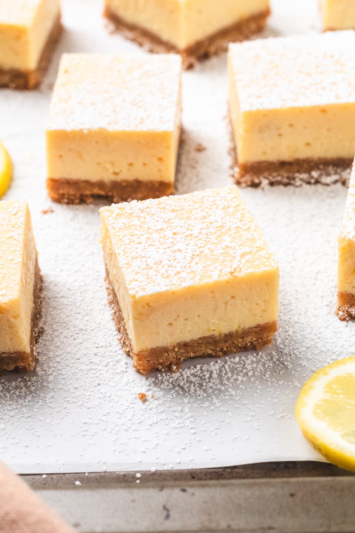 Lemon bars with a crumb crust and powdered sugar dusted on top.