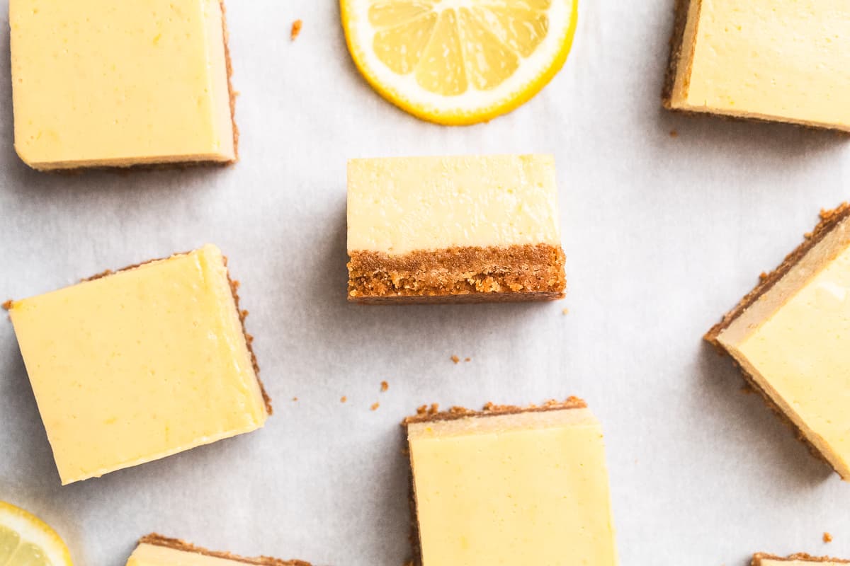 Lemon bars with graham cracker crust surrounded by fresh lemon slices.