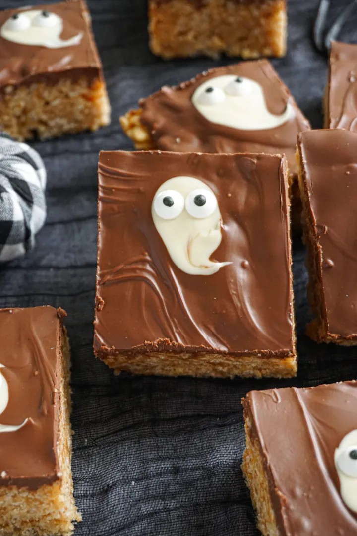 Chocolate rice krispie bars topped with candy eyes and white chocolate ghost shapes.