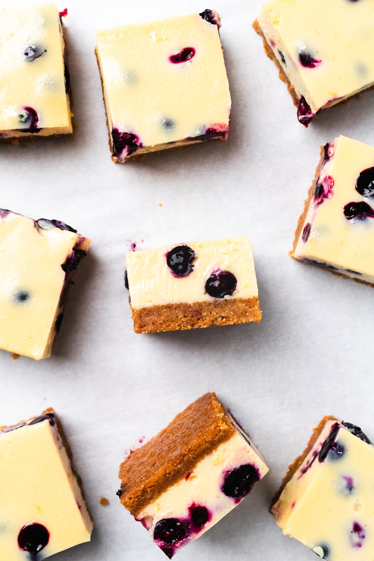 Lemon blueberry bars with creamy filling and fresh blueberries on a crust.
