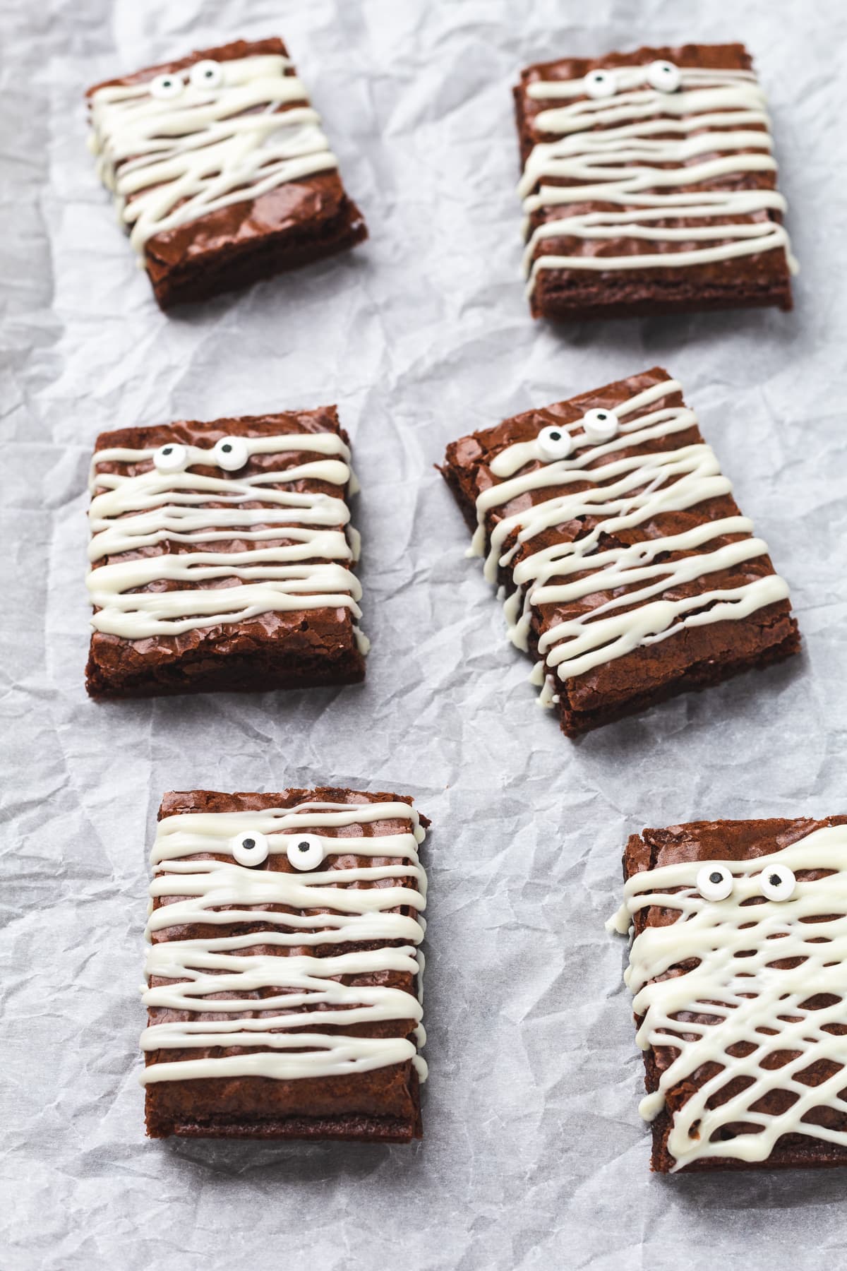 Halloween mummy brownies decorated with white chocolate stripes and candy eyes.