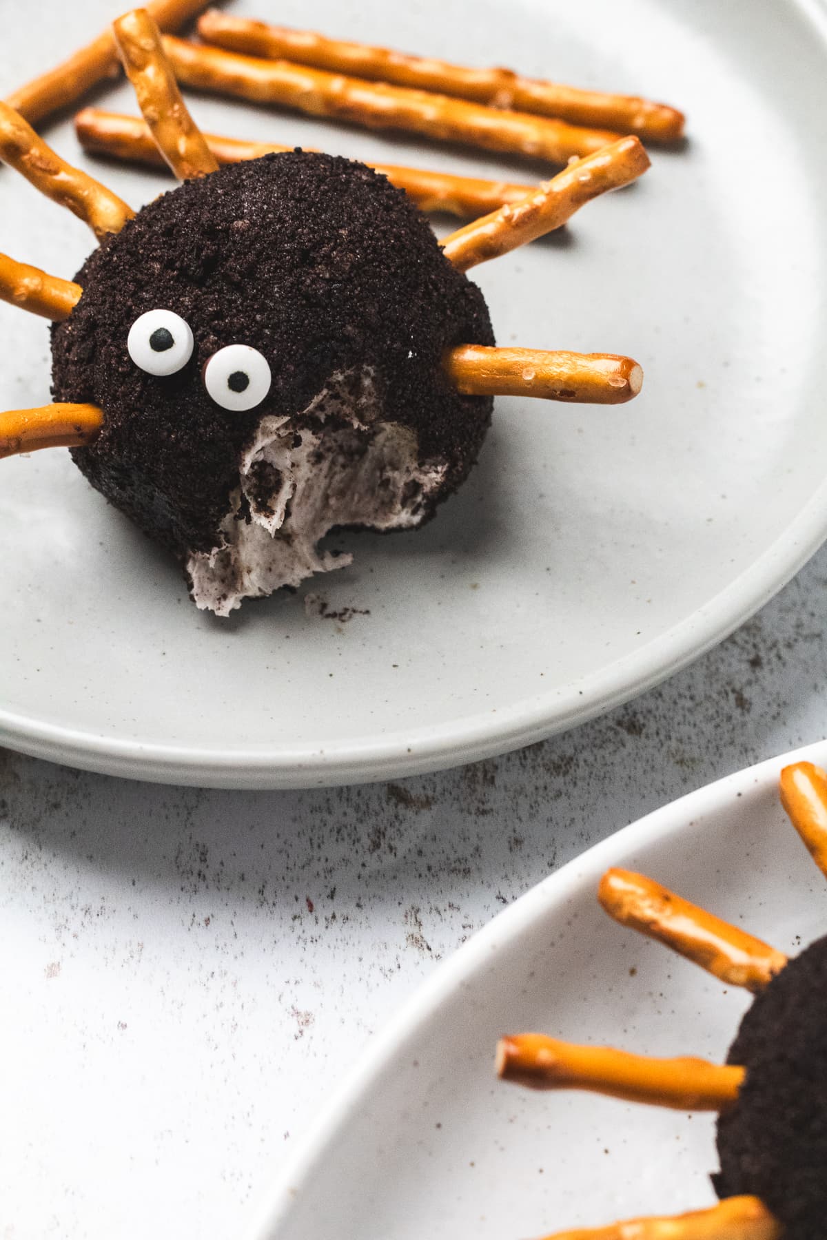 Close-up of a spider cheeseball with a bite taken out, showing creamy filling inside.