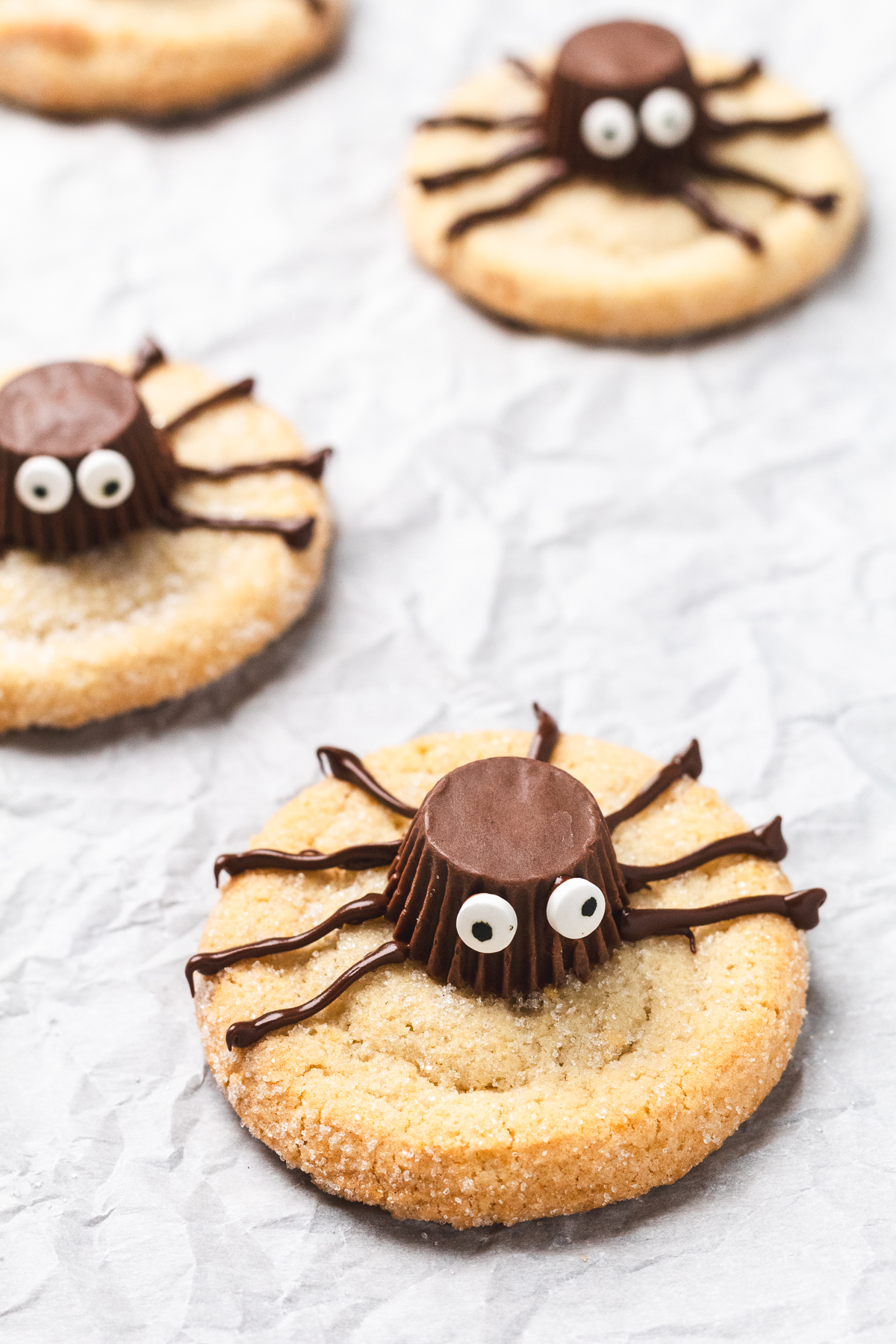 Close-up of Halloween spider cookies made with peanut butter cups, candy eyes, and chocolate legs.