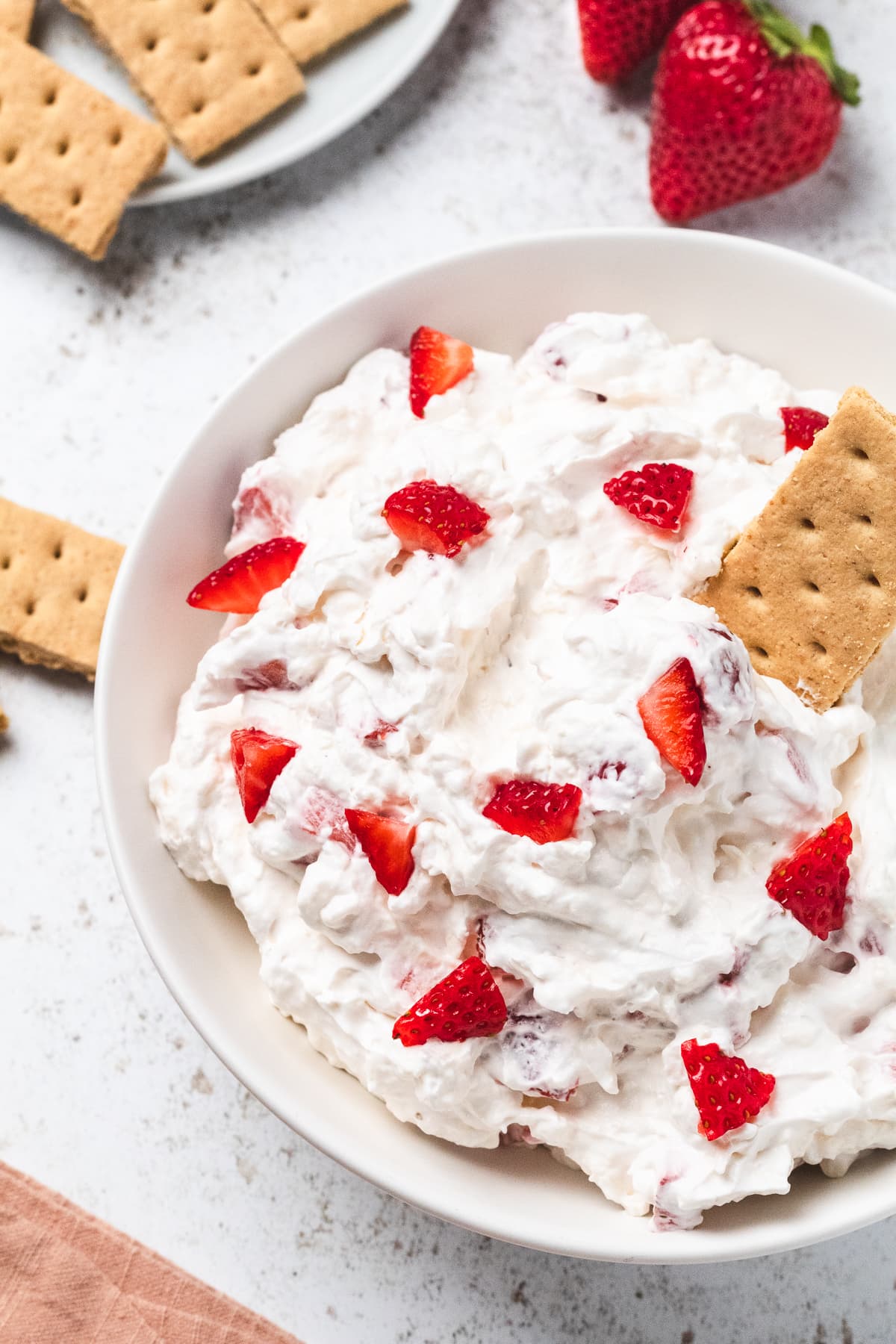 Overhead view of strawberry cheesecake dip with fresh strawberries and graham crackers.