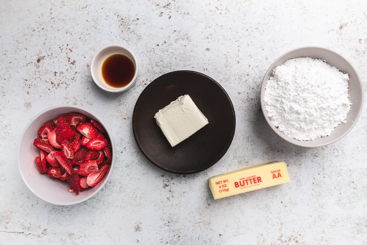 Strawberry cheesecake frosting ingredients including butter, cream cheese, sugar, vanilla, and strawberries.