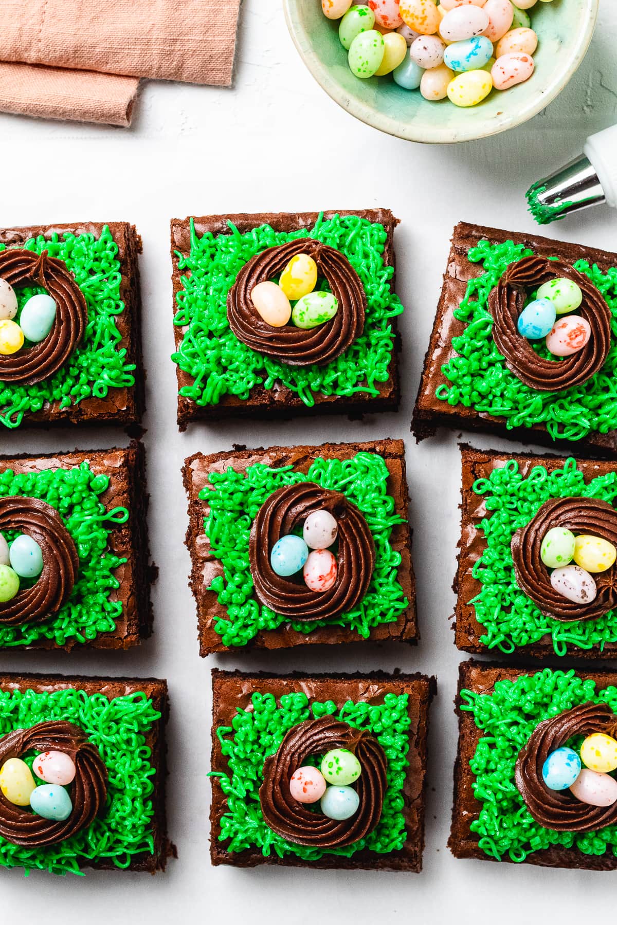 Overhead view of Easter brownies with chocolate nests and jelly bean eggs on green frosting grass.