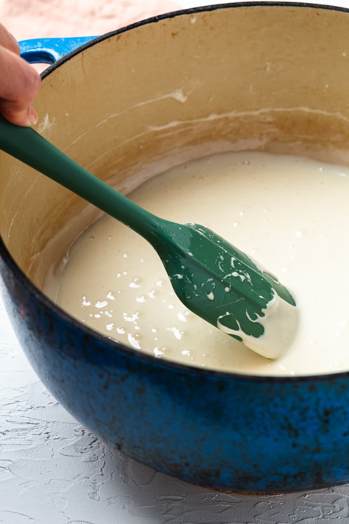 Stirring melted marshmallows and butter in a blue pot for Lucky Charms treats.