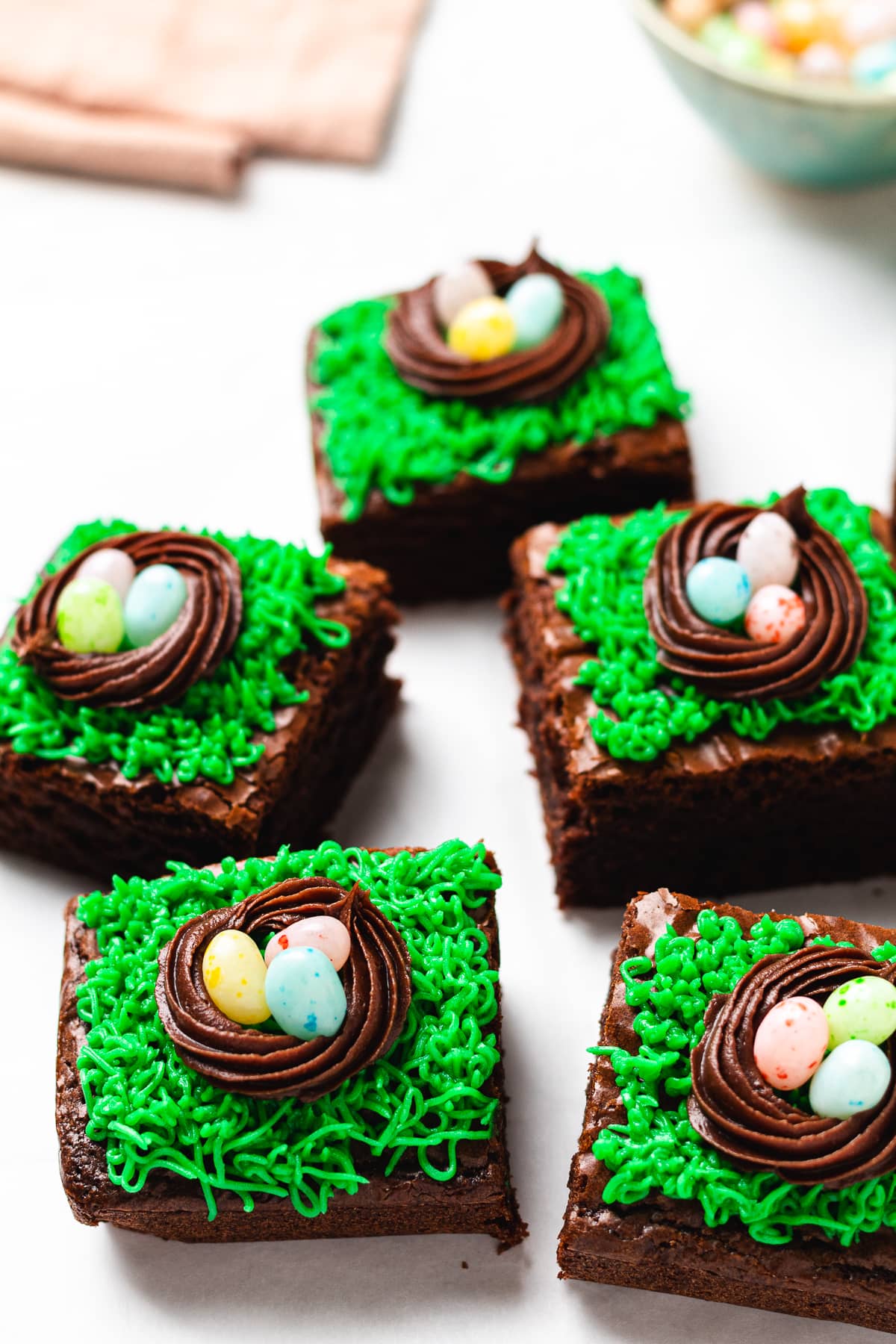 Easter brownies topped with green frosting grass, chocolate nests, and jelly bean eggs.