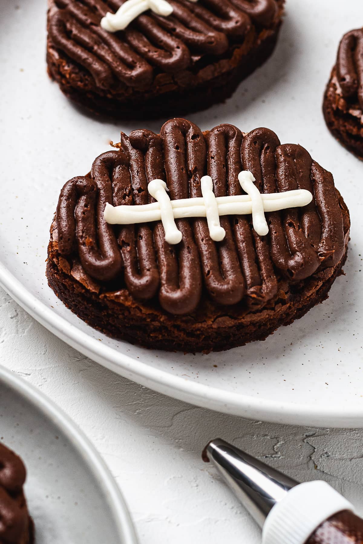 Close-up of football brownies with chocolate frosting and white icing laces on plate.