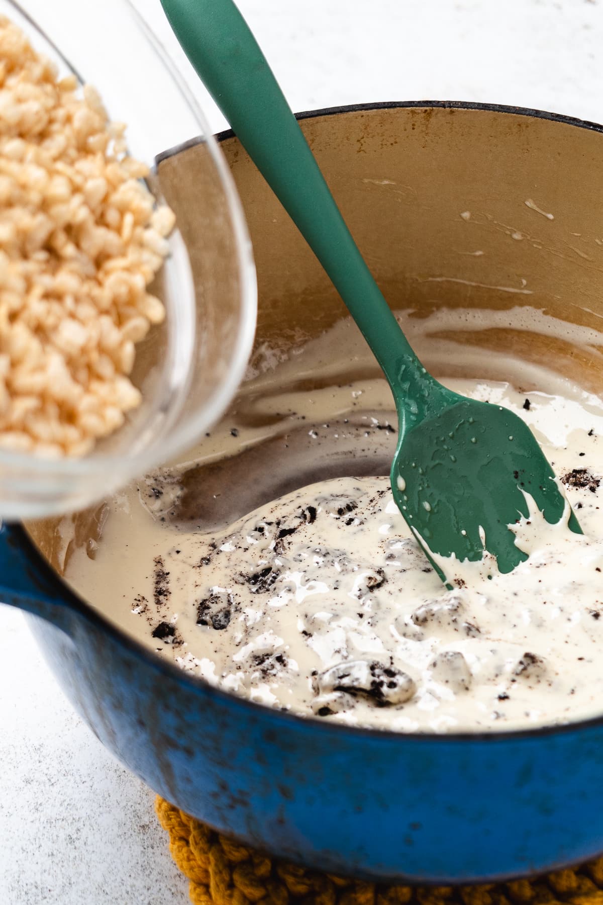 Rice Krispies being poured into the melted marshmallow and crushed Oreo mixture.