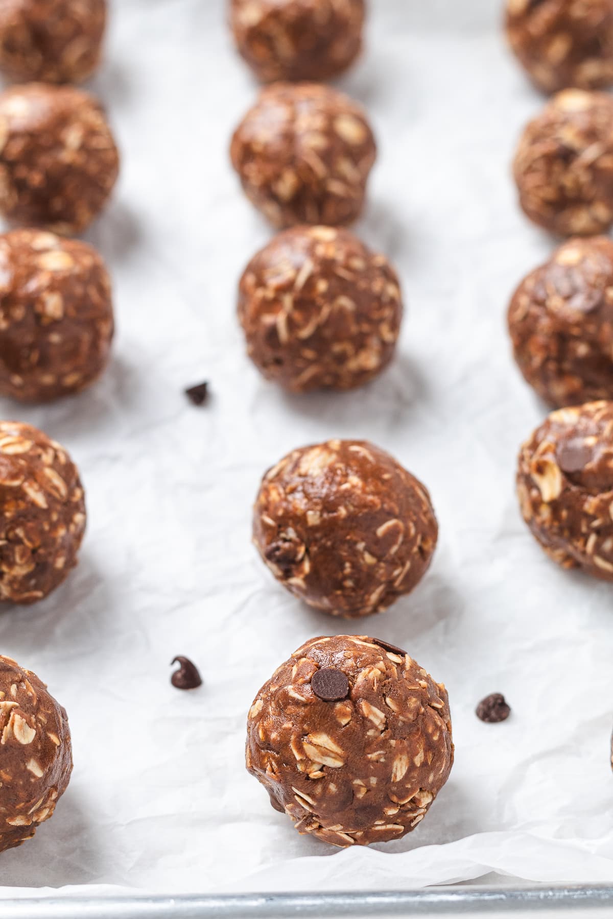 Chocolate protein balls arranged on a parchment-lined baking sheet.