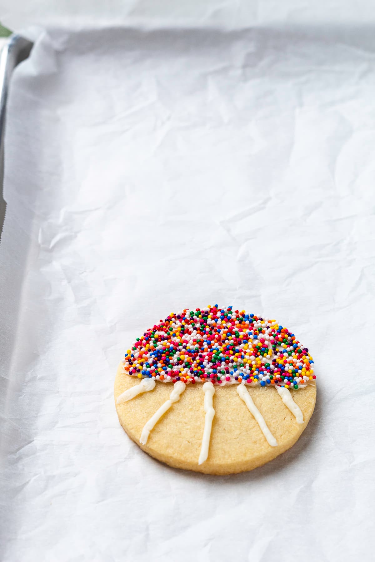 Adding white frosting lines to football stadium cookie before green frosting.