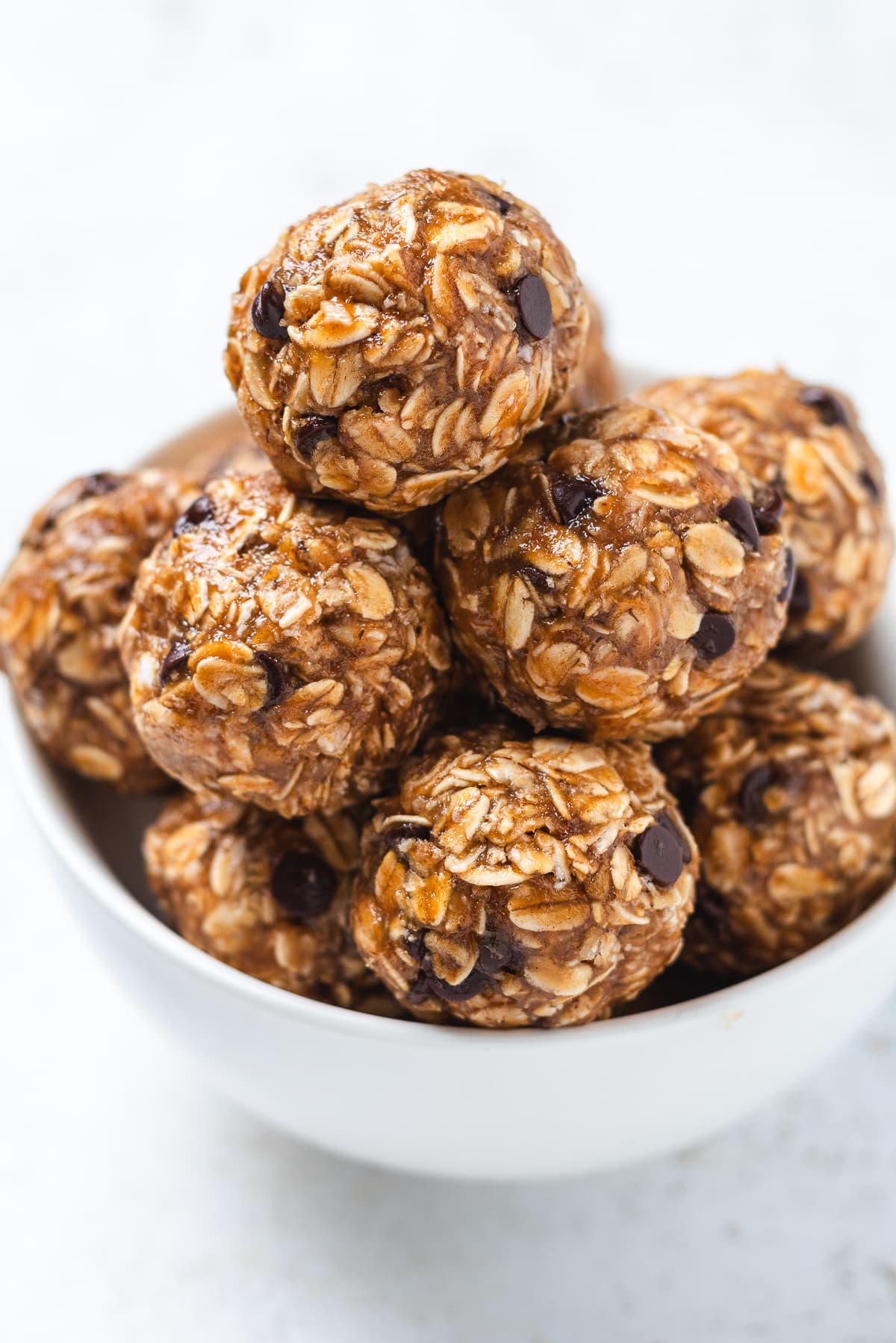 Bowl stacked with finished banana protein balls studded with chocolate chips.