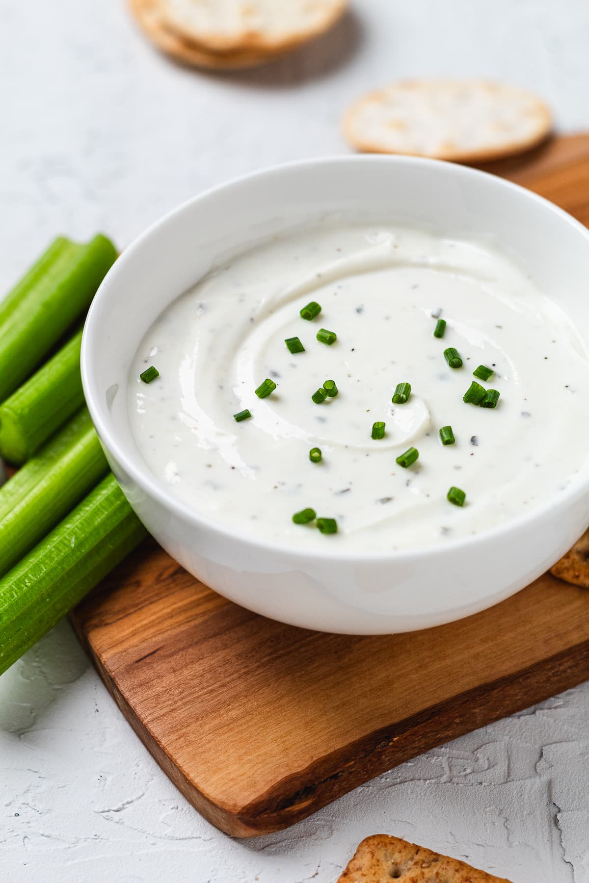 Creamy Greek yogurt ranch dip garnished with chives, served with celery sticks and crackers.