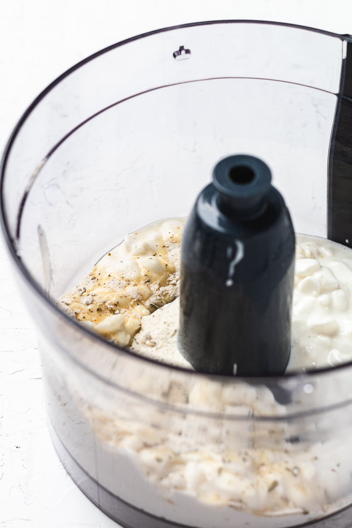 Food processor with cottage cheese, seasonings, and other dip ingredients before blending.