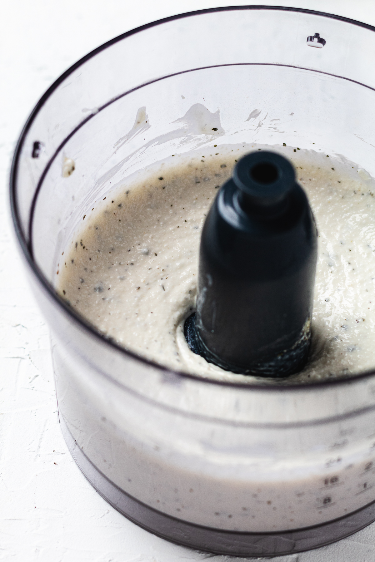 Blended cottage cheese ranch dip inside a food processor bowl, smooth and creamy with visible seasoning.