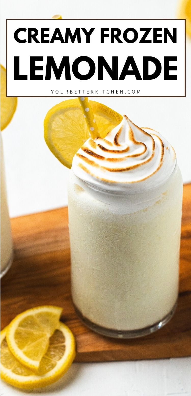 Glass of creamy frozen lemonade topped with toasted meringue and lemon slice, with text โCreamy Frozen Lemonadeโ