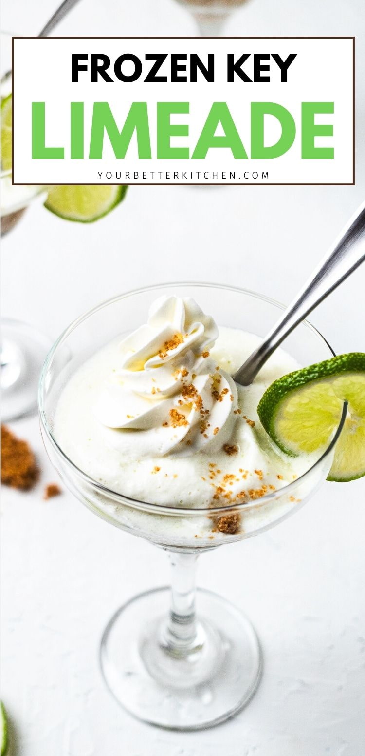 Glass coupe of frozen key limeade topped with whipped cream and brown sugar crumbs, garnished with a lime slice.