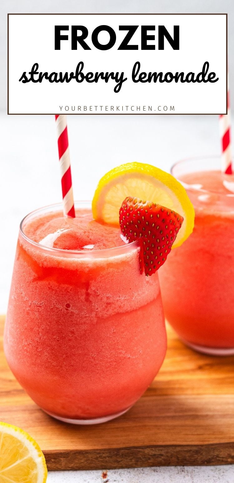 Two glasses of frozen strawberry lemonade with striped straws, lemon slice and strawberry garnish on a wooden board.
