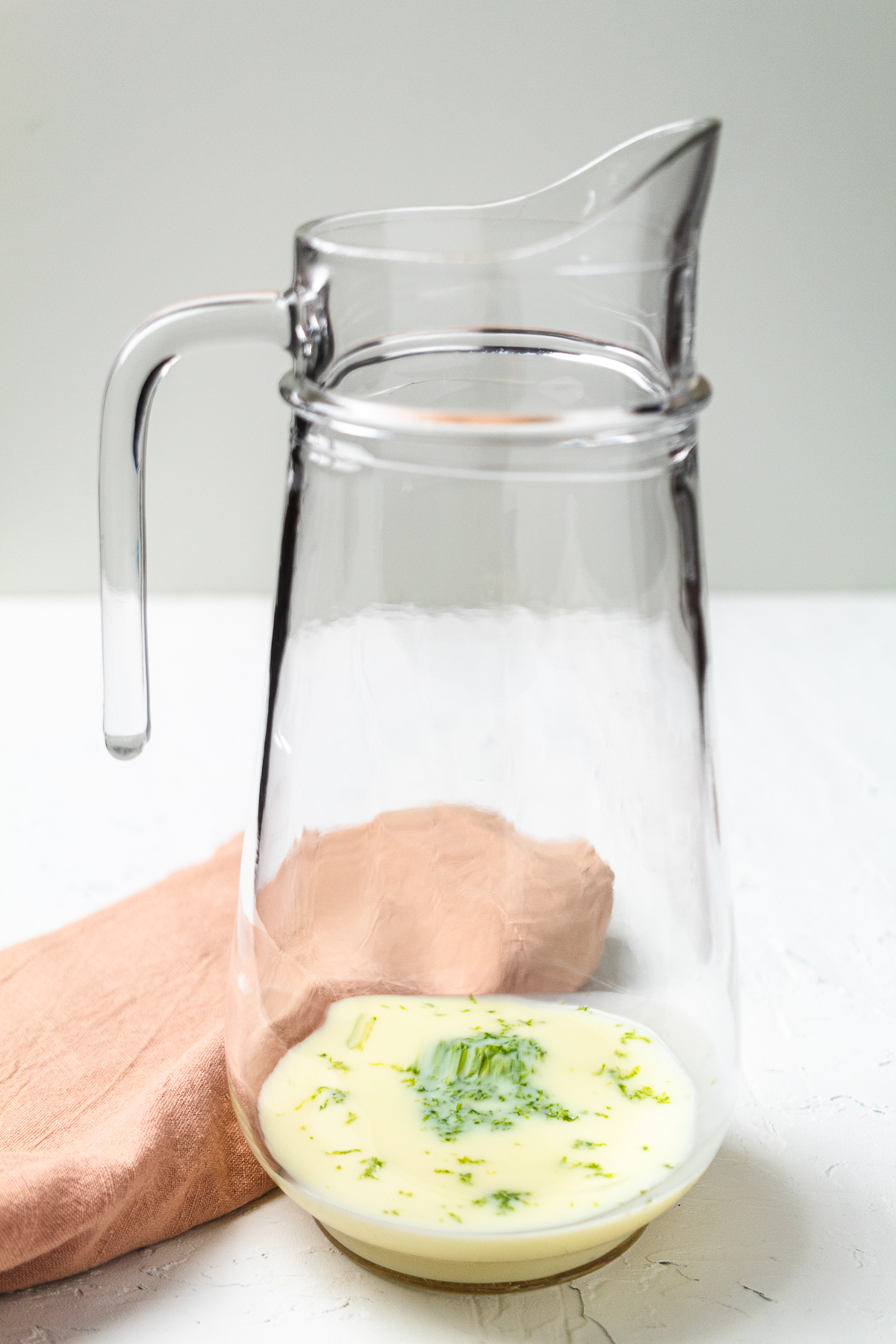 Creamy Brazilian lemonade base in pitcher with lime zest and condensed milk, pin shows refreshing lime drink recipe.