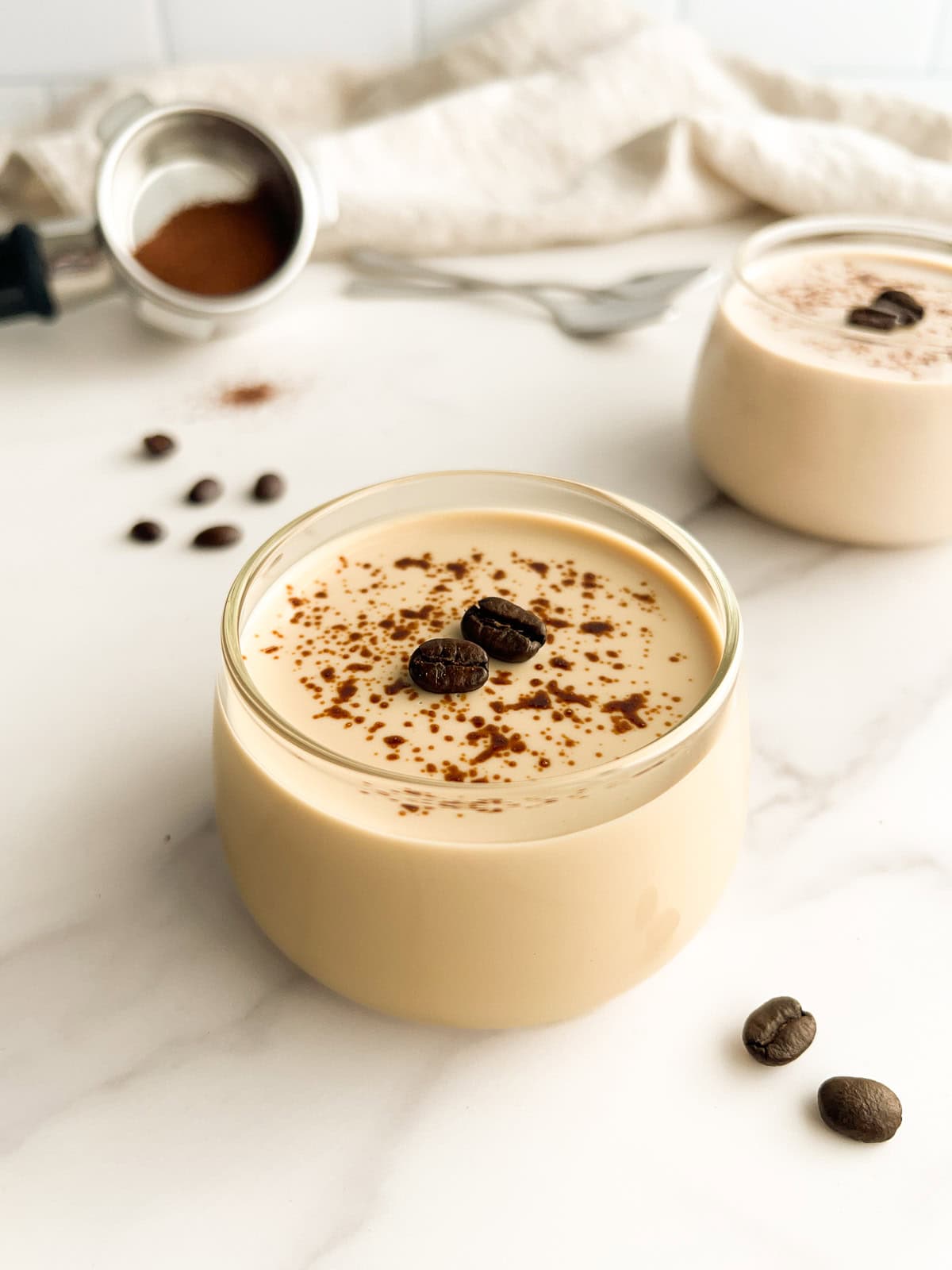 Coffee panna cotta dessert topped with cocoa powder and coffee beans in glass cups.