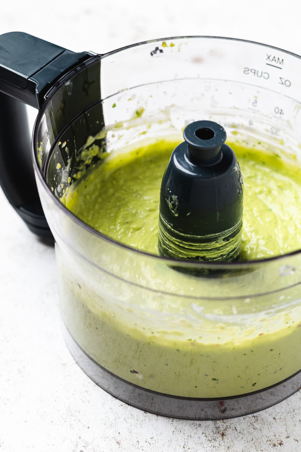 Food processor filled with smooth light green blended mixture.