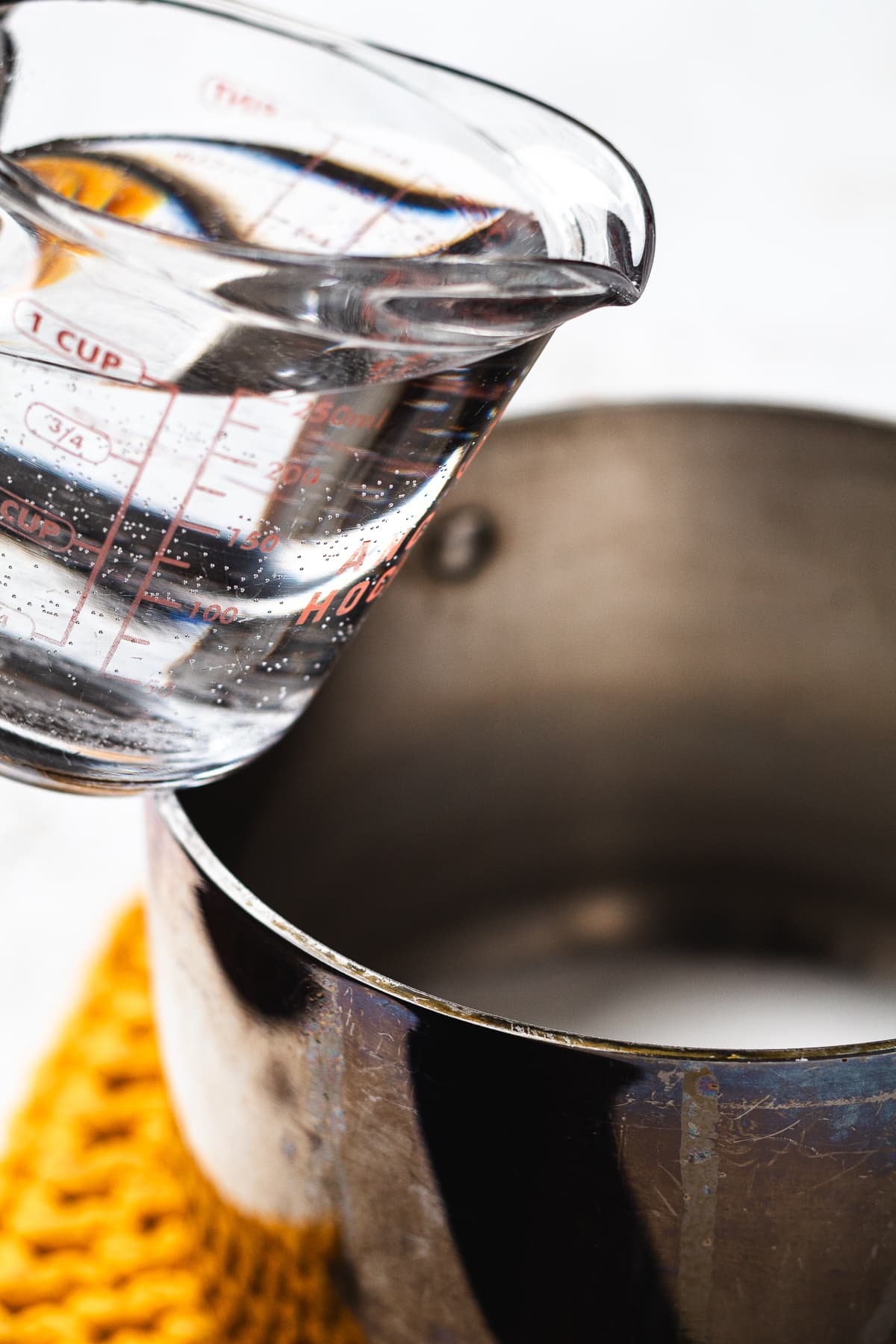 Pouring water into saucepan to make simple syrup for homemade lemonade.