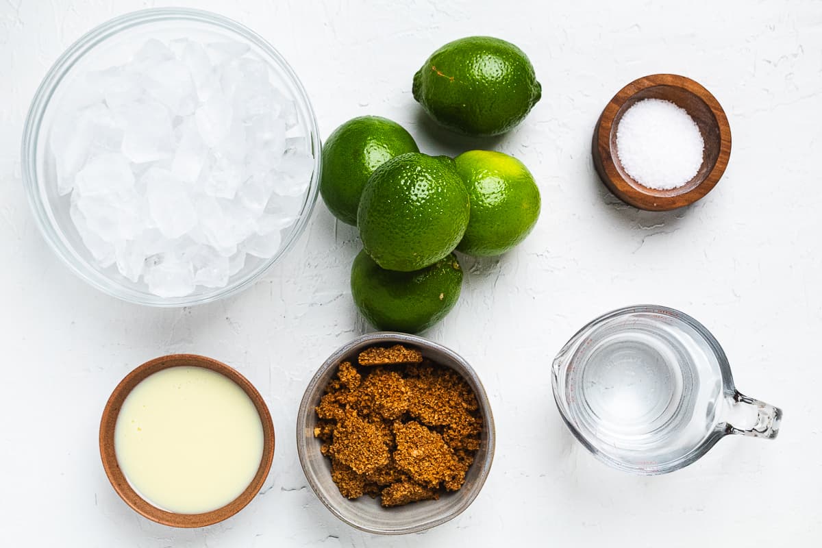 Ingredients for frozen key limeade: limes, condensed milk, sugar, ice, and water, pin shows simple recipe.