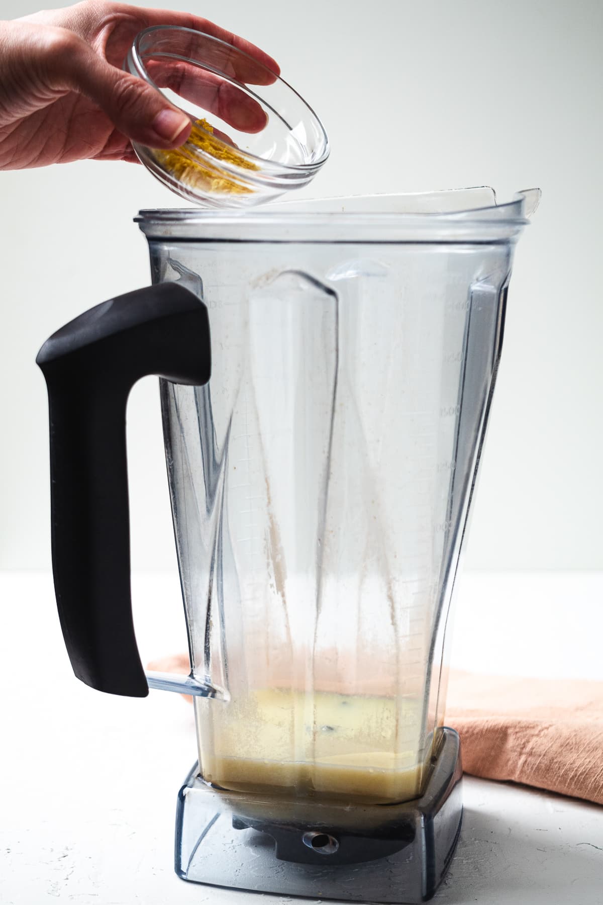 Hand adding lemon zest into blender with lemonade mixture for frozen lemon drink.
