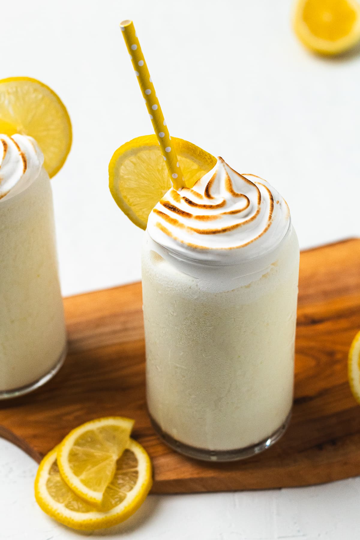 Frozen lemon meringue lemonade topped with toasted meringue and lemon slice, served with a yellow straw.