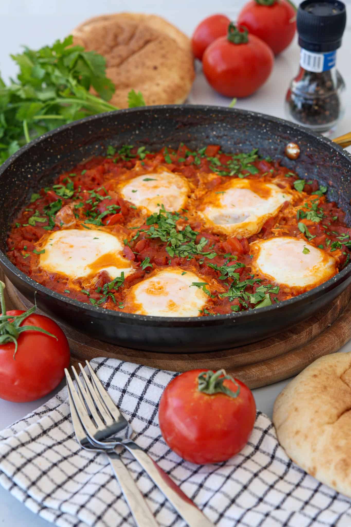 Shakshuka with eggs poached in tomato sauce, topped with herbs in a skillet.