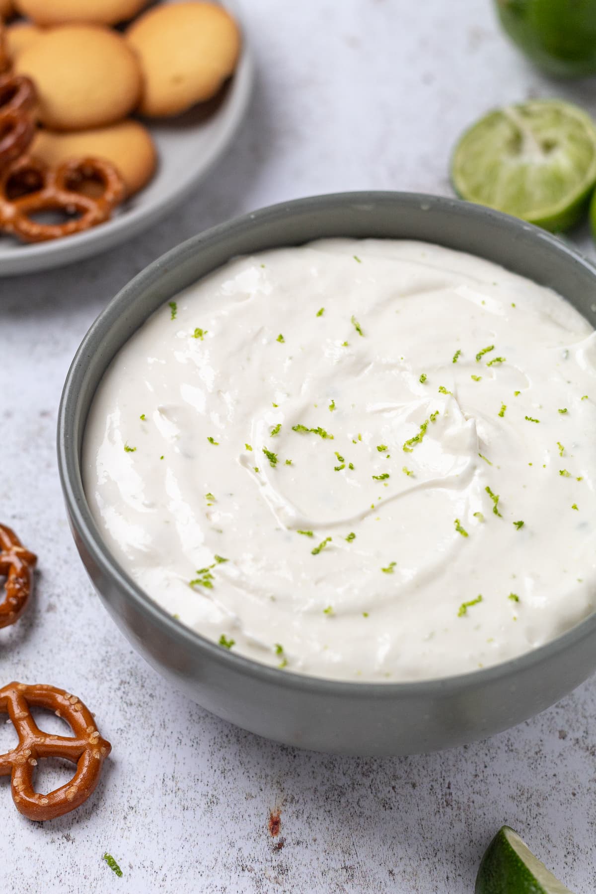 Creamy margarita dip in bowl with lime zest and pretzels.