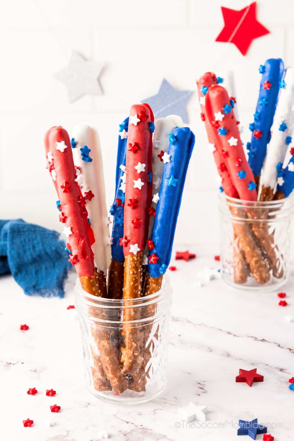 Red, white, and blue chocolate-covered pretzel rods with festive sprinkles.