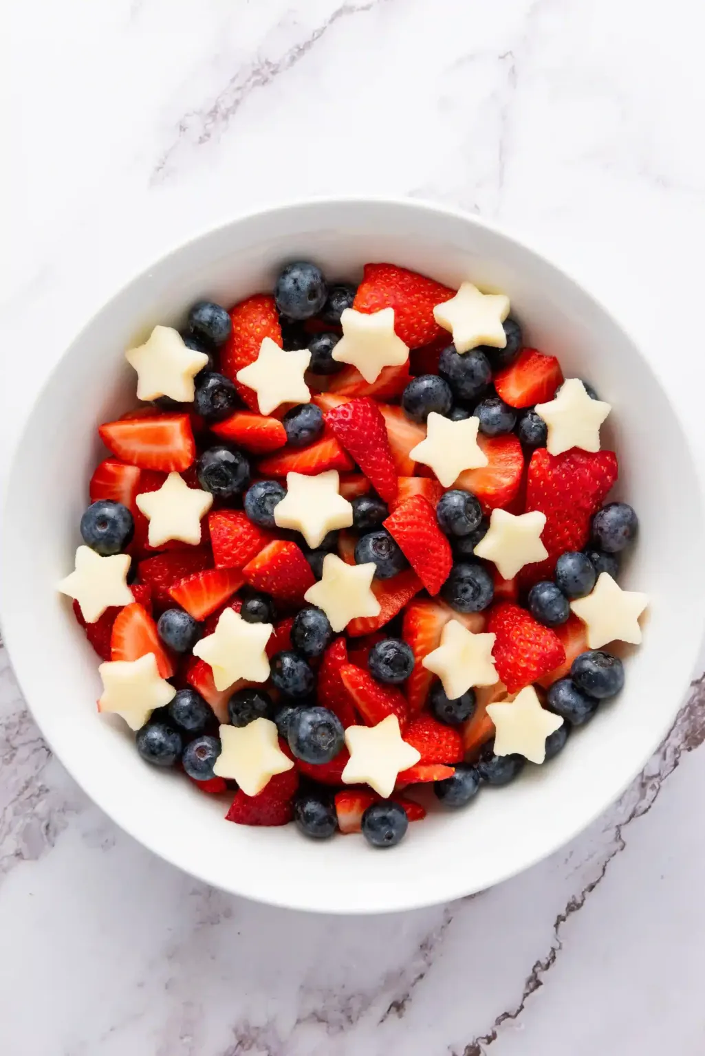 Patriotic fruit salad with strawberries, blueberries, and star-shaped fruit pieces.