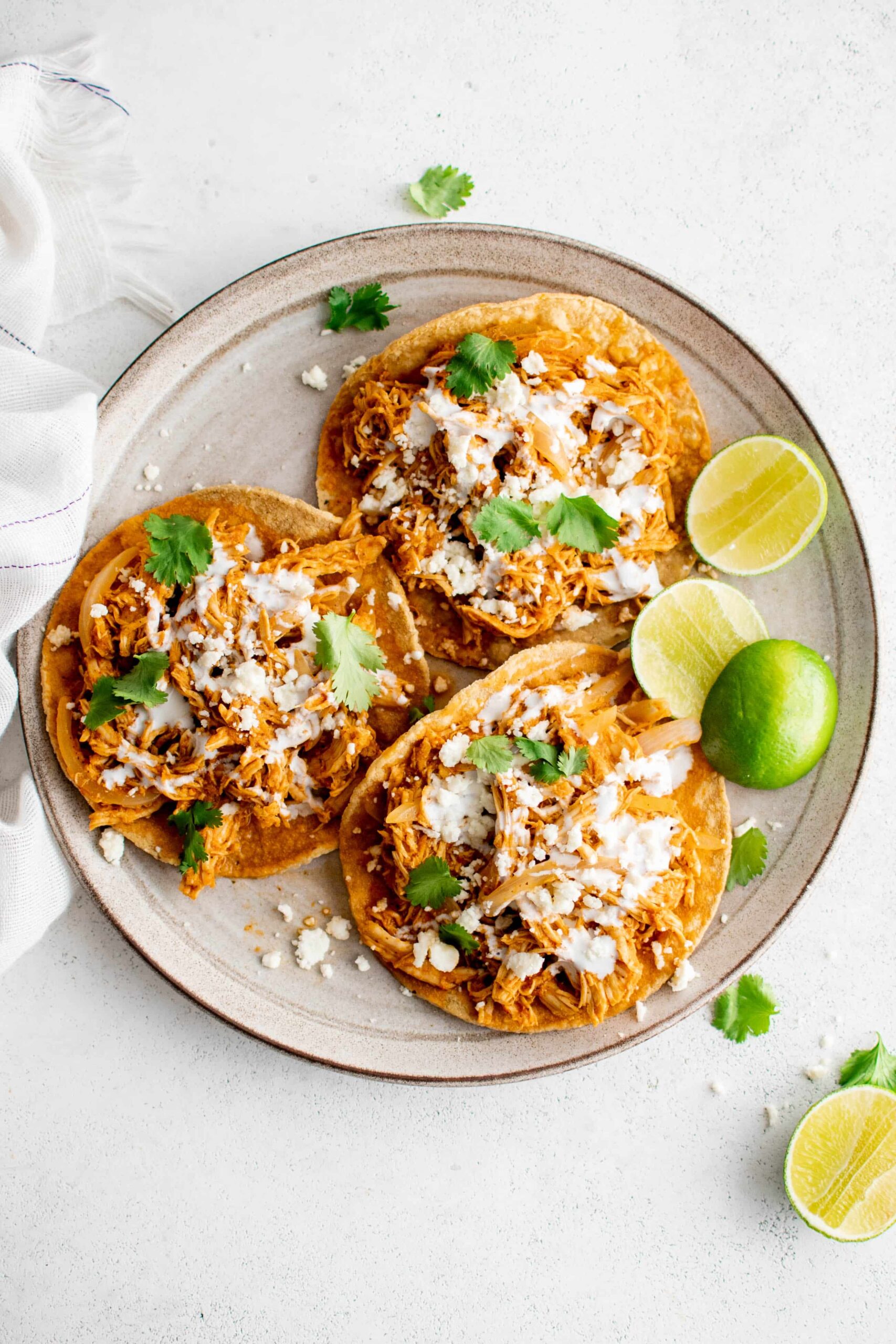 Chicken tinga tostadas topped with cheese, crema, and fresh cilantro.