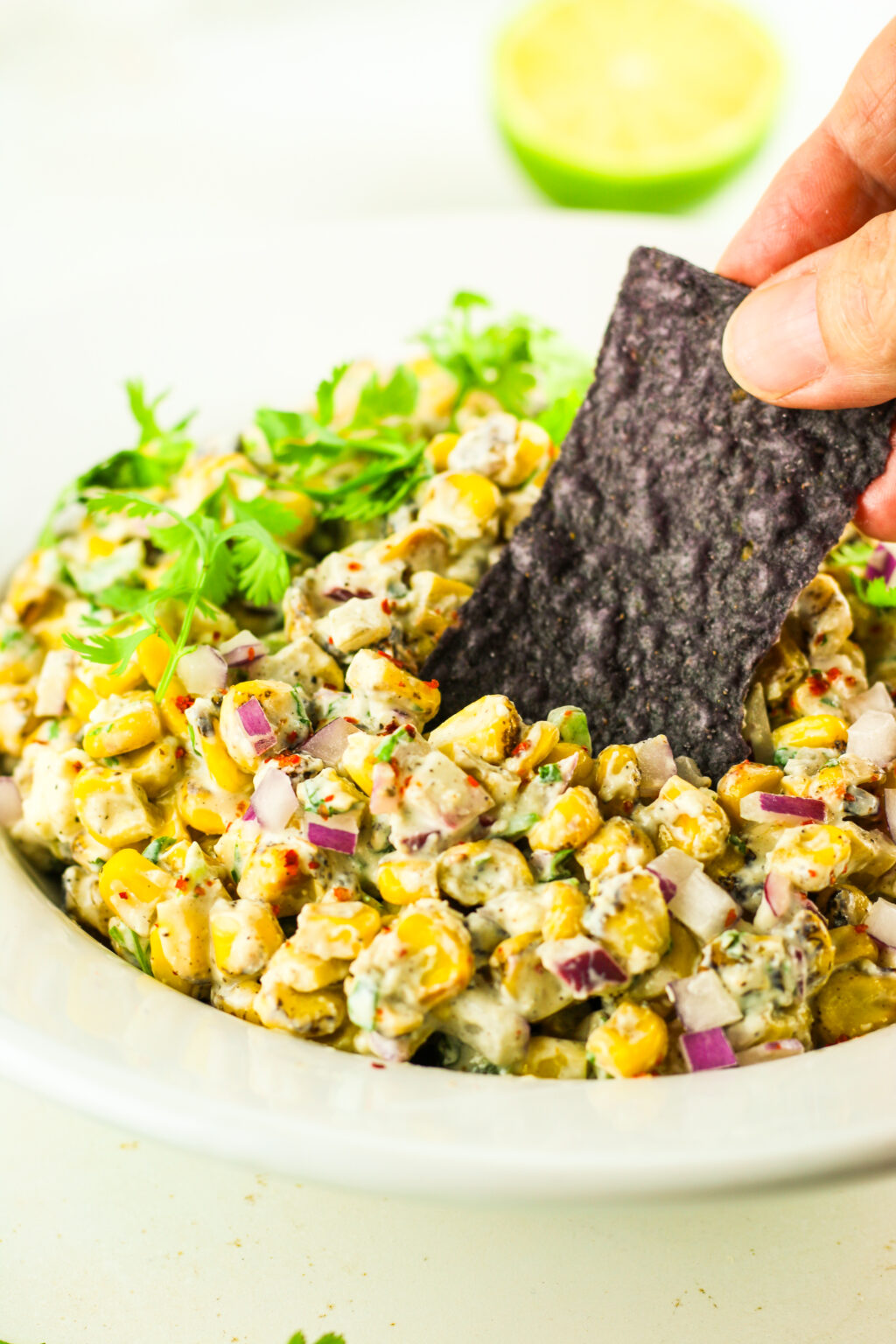 Creamy Mexican street corn salad with corn, cheese, cilantro, and red onion served with chips.