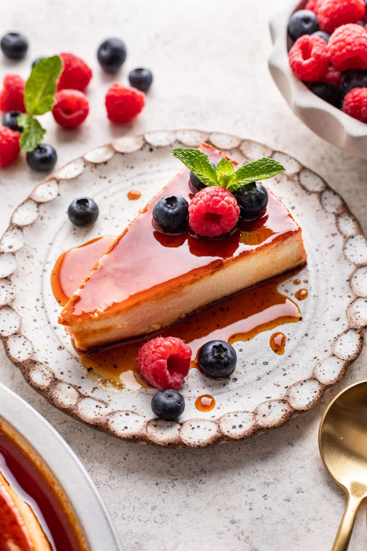 Slice of flan topped with caramel sauce and fresh berries.