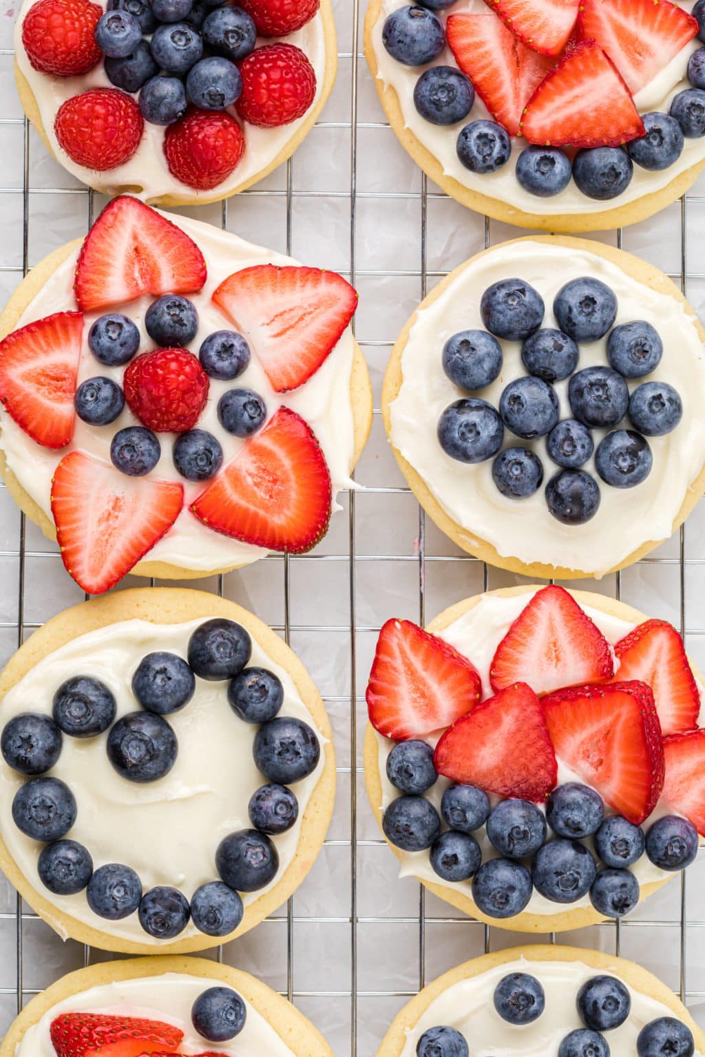 Sugar cookies with frosting topped with strawberries and blueberries.