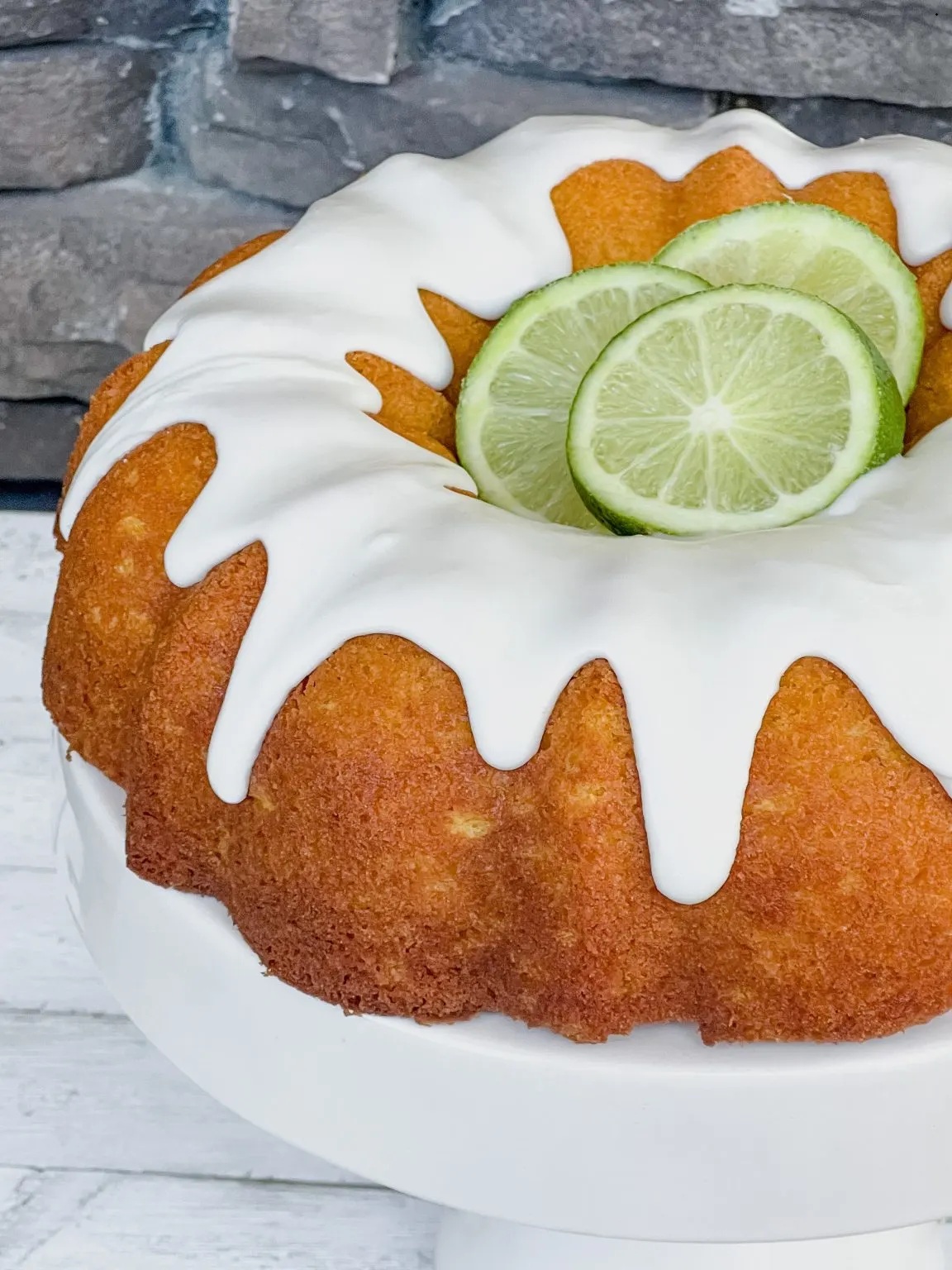 Bundt cake with white glaze and lime slices on top.