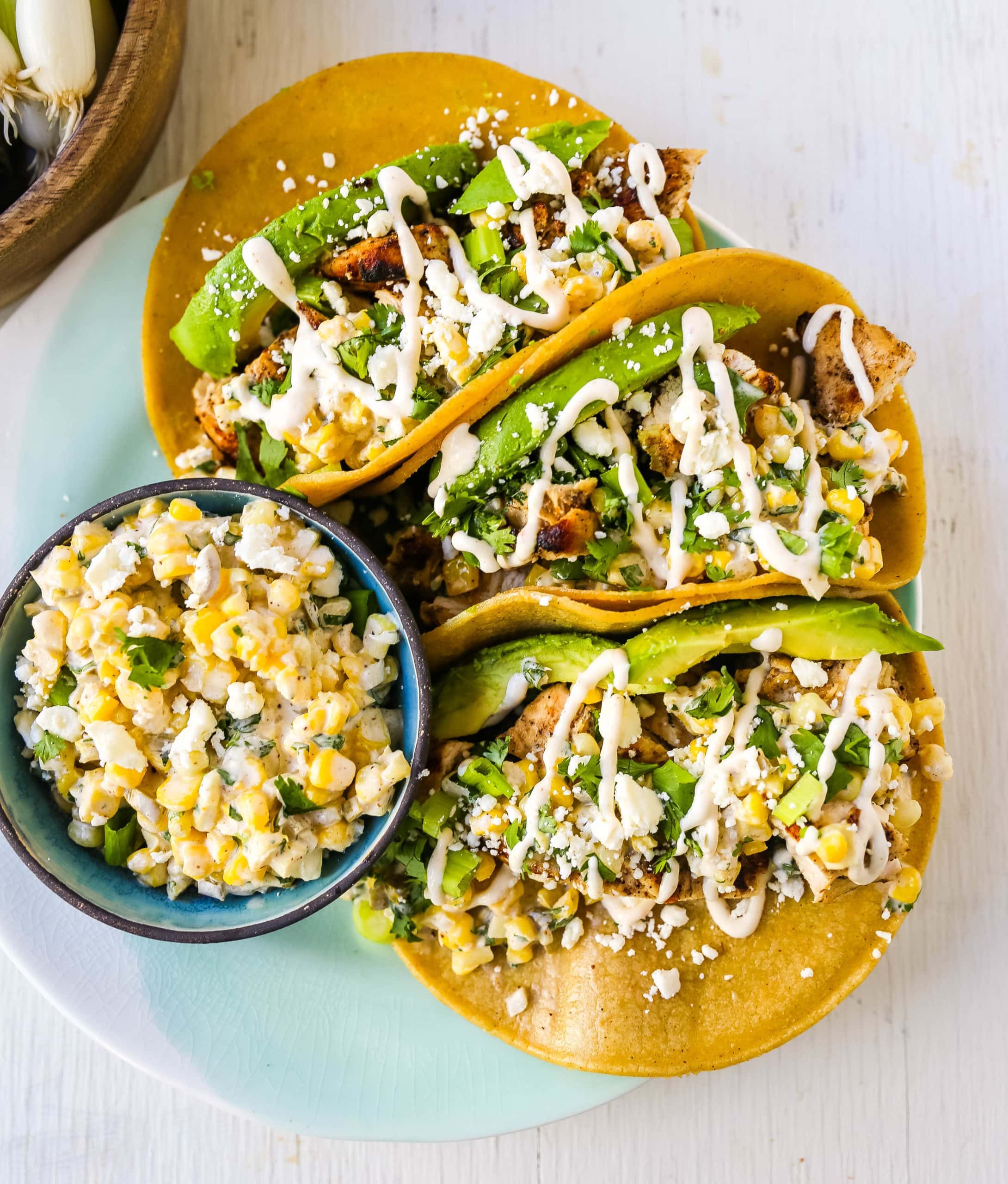 Street corn chicken tacos topped with avocado, cheese, and creamy drizzle.