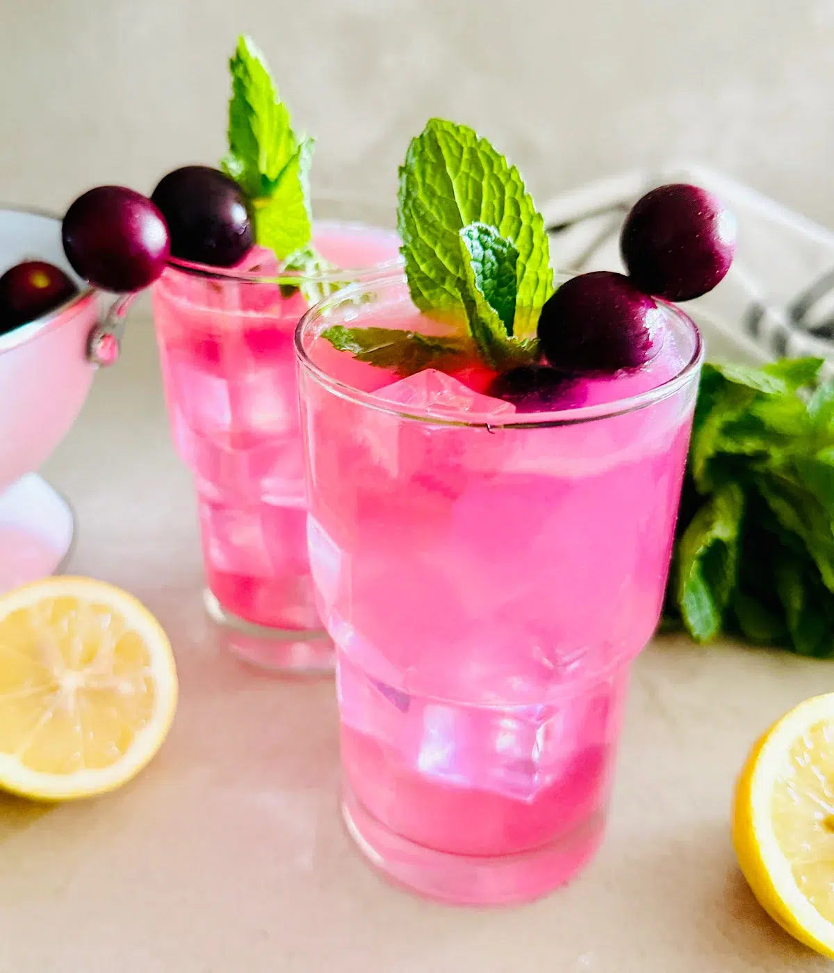 Pink muscadine lemonade in glasses garnished with grapes and mint leaves.