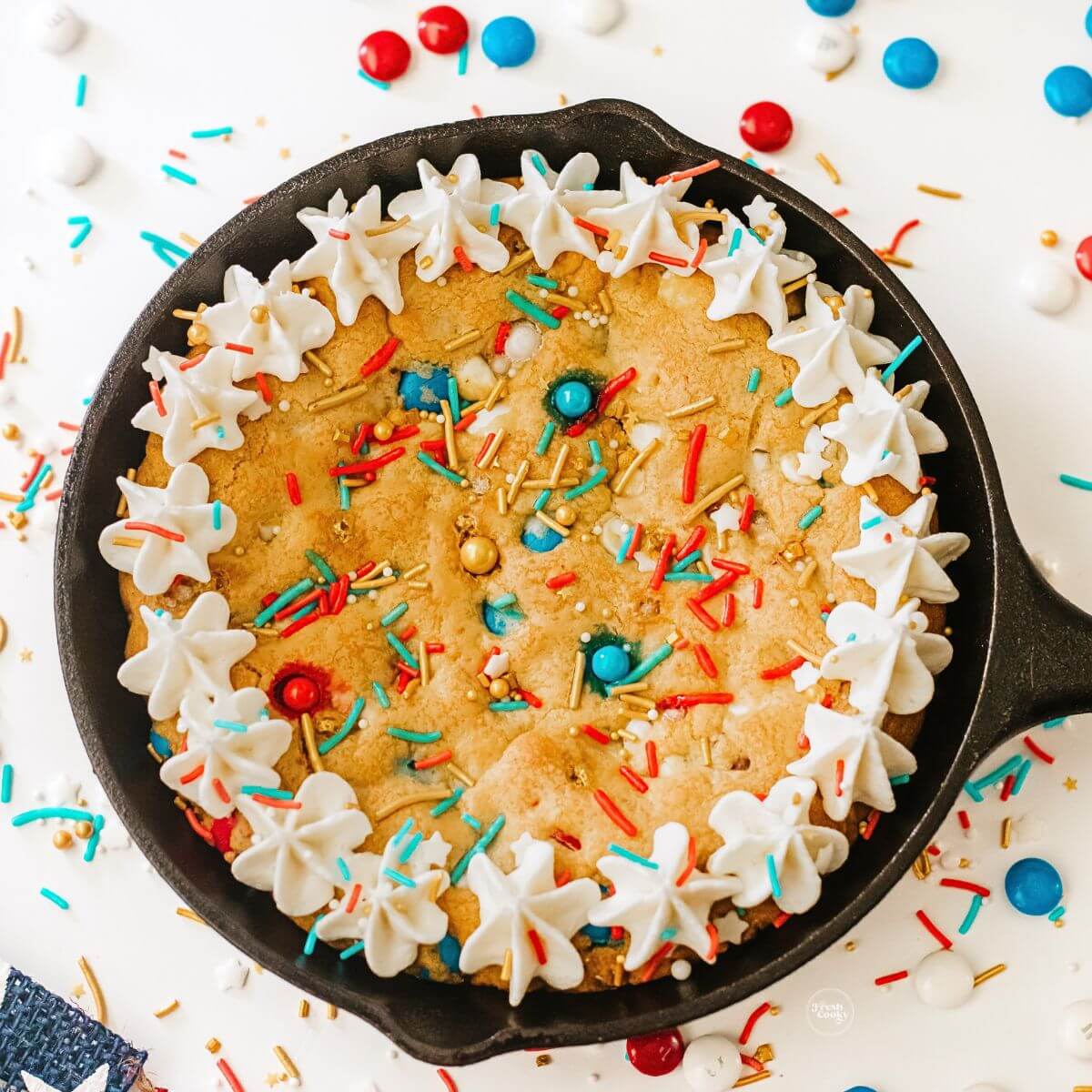 Skillet cookie cake with white frosting border and red, white, blue sprinkles.