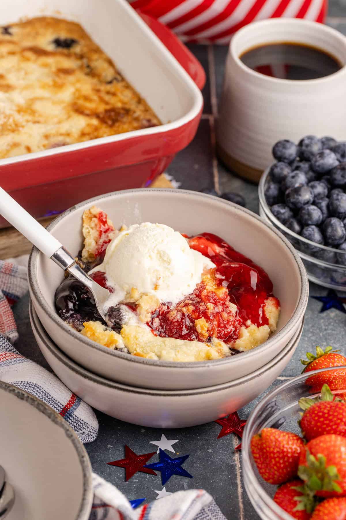 Berry dump cake with strawberries and blueberries topped with vanilla ice cream.