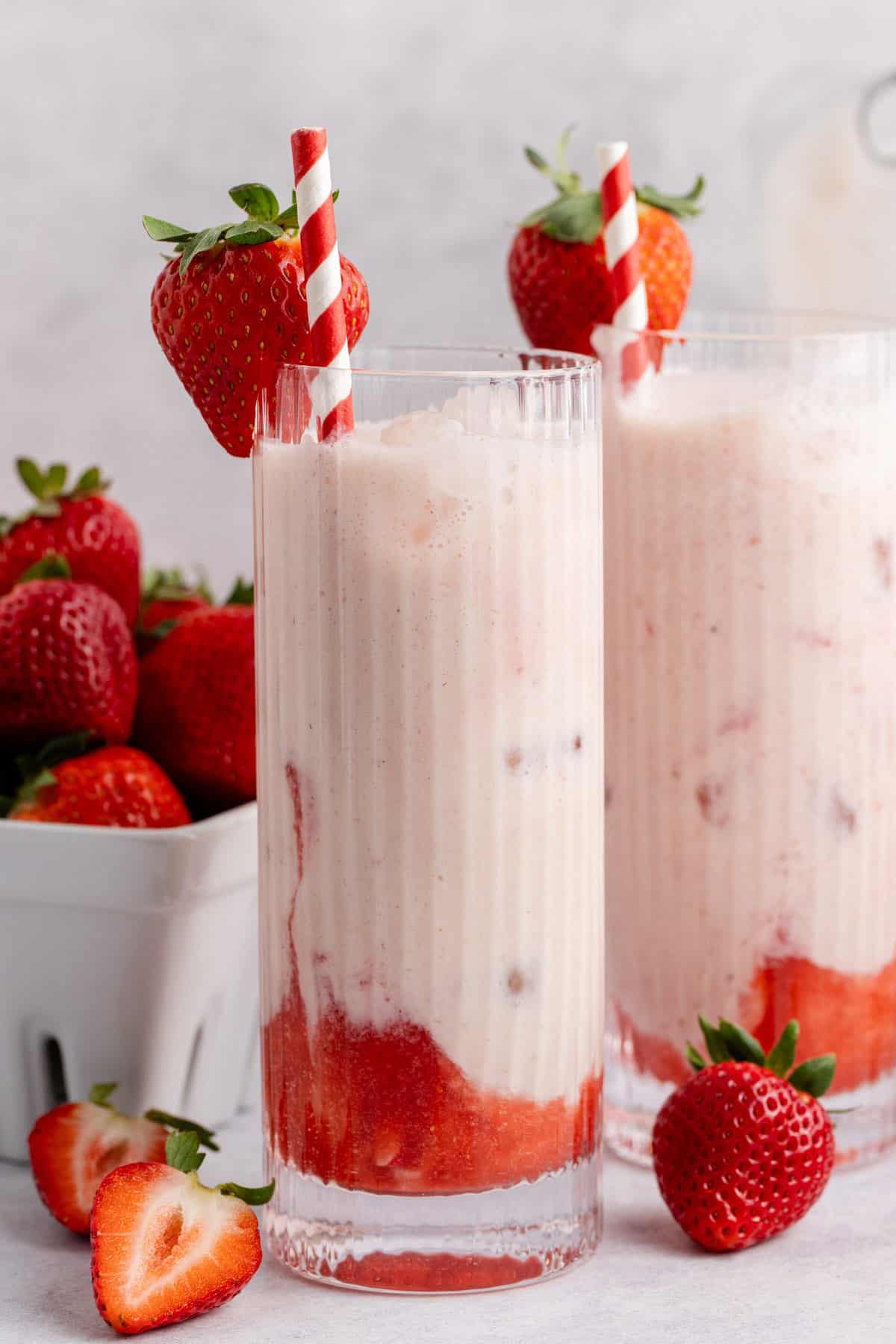 Strawberry horchata in a glass with fresh strawberries and a striped straw.