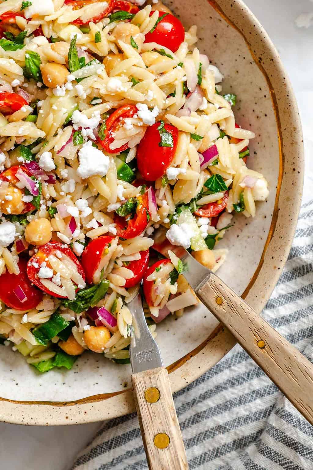 Mediterranean orzo pasta salad with chickpeas, tomatoes, herbs, and feta.
