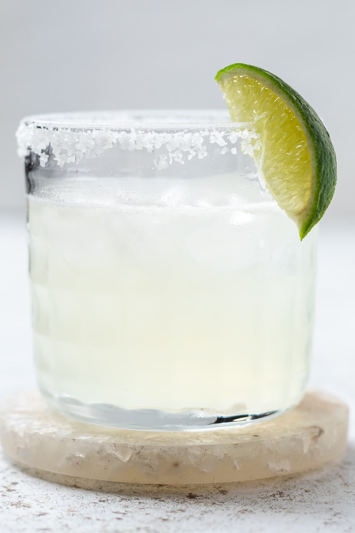 Close-up image of a classic margarita in a salt-rimmed glass with a fresh lime wedge.