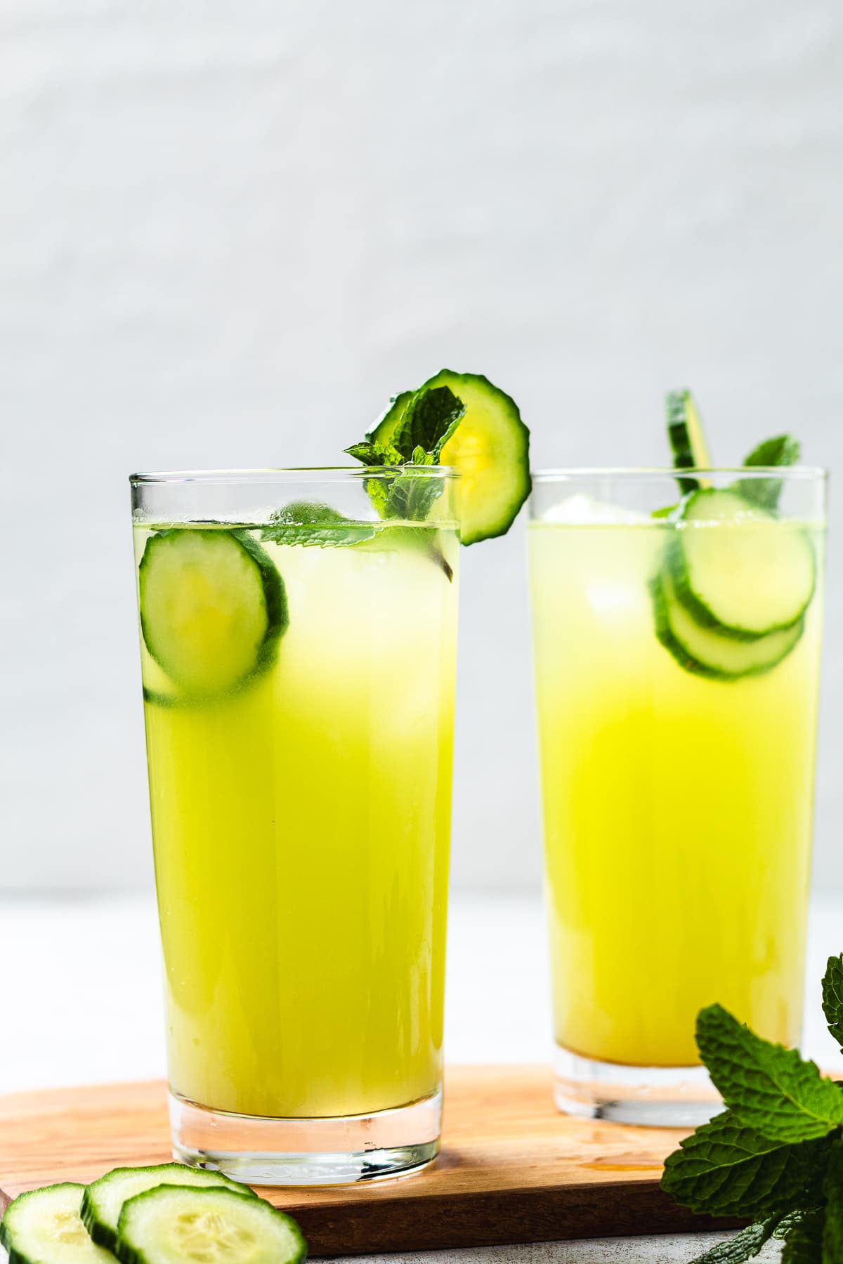 Two glasses of cucumber agua fresca with lime slices and fresh mint.