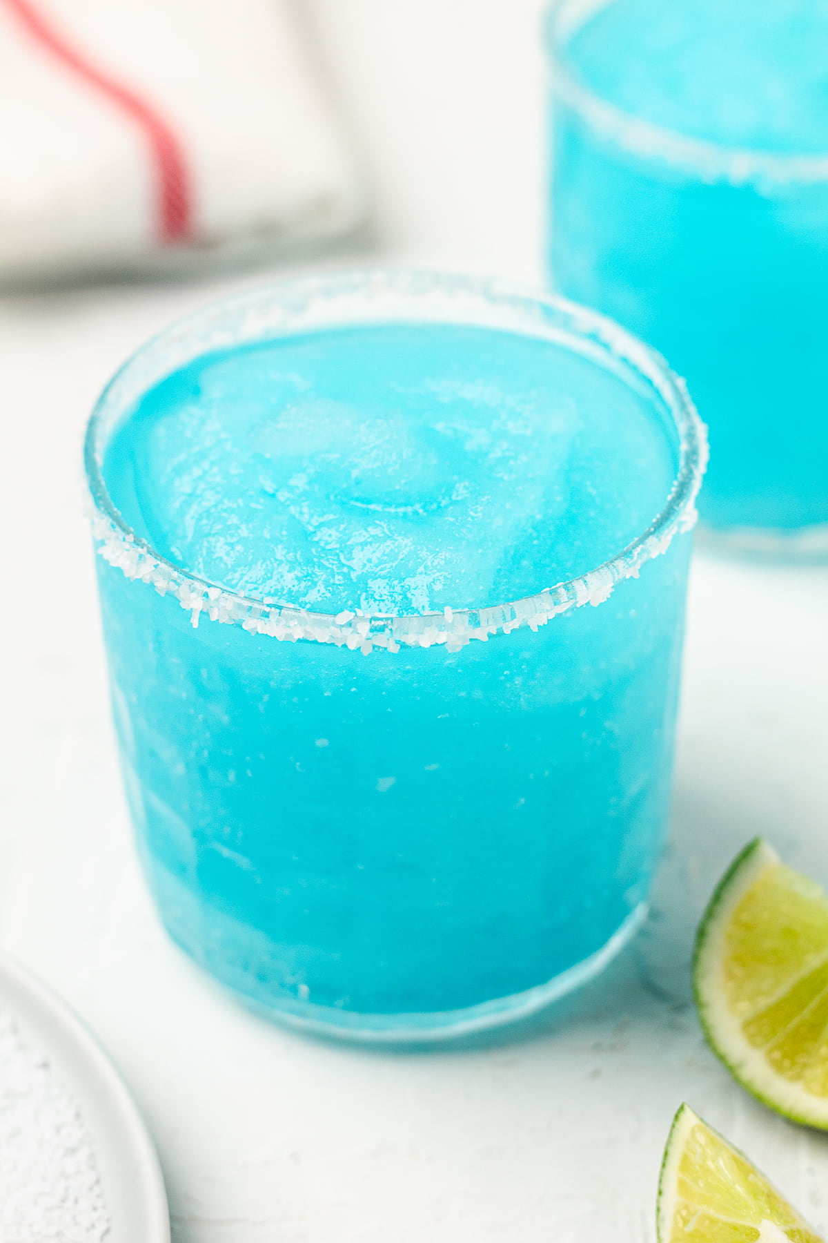 Image of blue margaritas with salt and slices of lime.