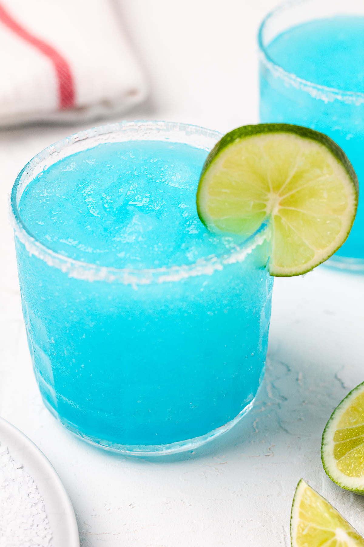 Frozen blue margarita with a salted rim and lime wedge garnish.